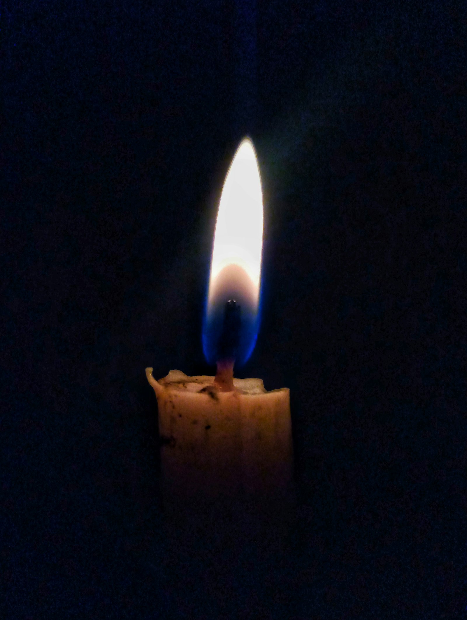 A single lit candle glowing softly against a dark background